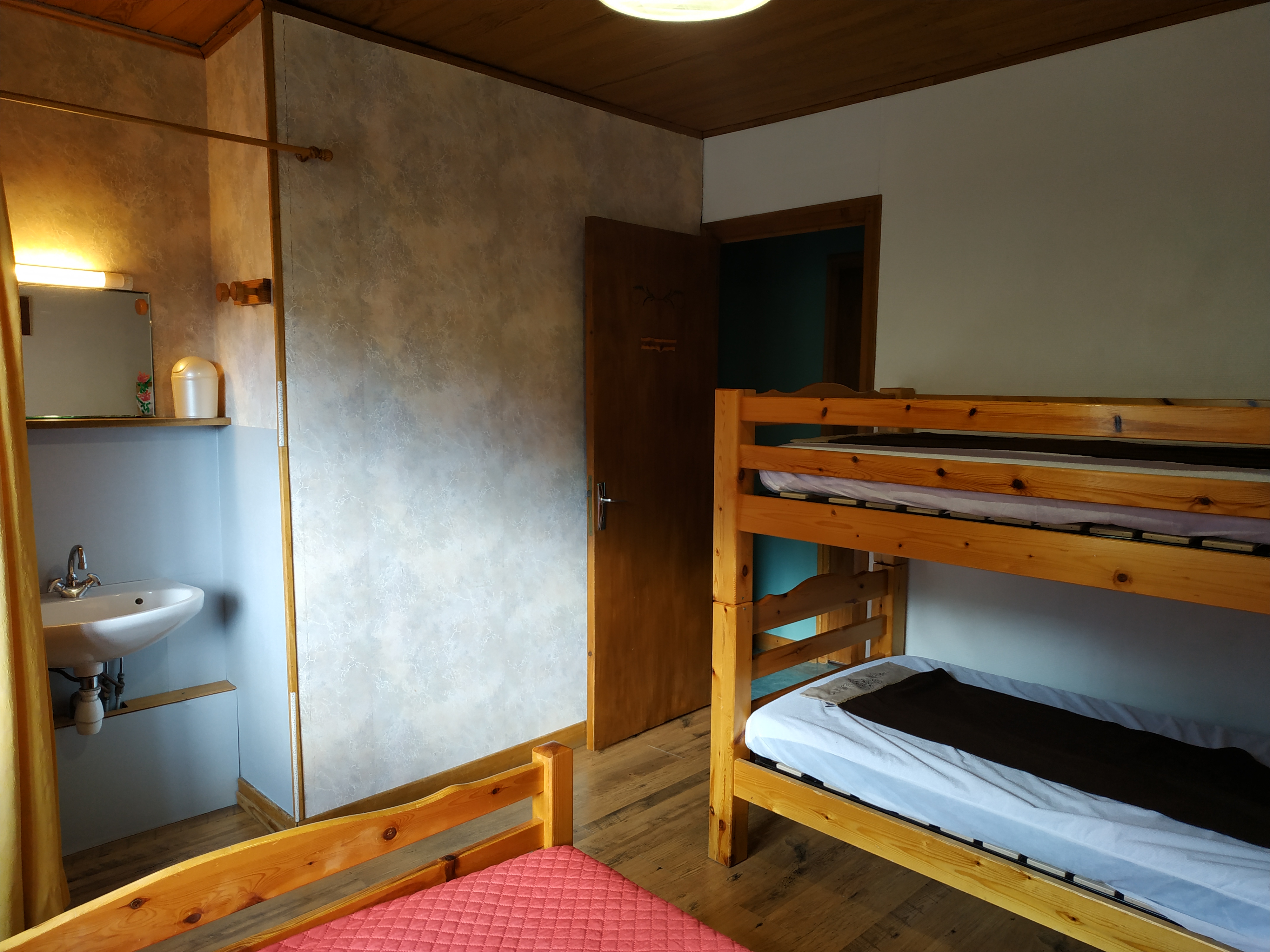 Chambre Petit Som avec un lit double, deux lits simples superposés et un lavabo